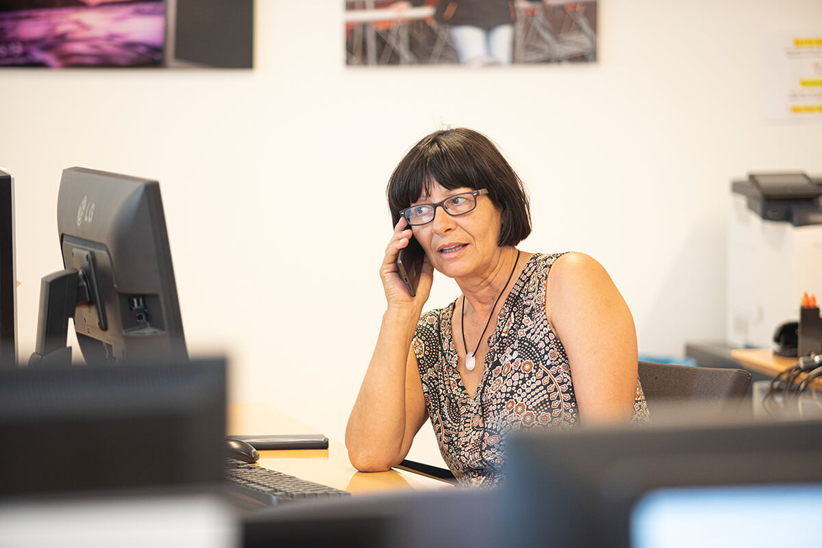 Eine Personalberaterin sitzt an ihrem Arbeitsplatz vor dem PC und telefoniert.