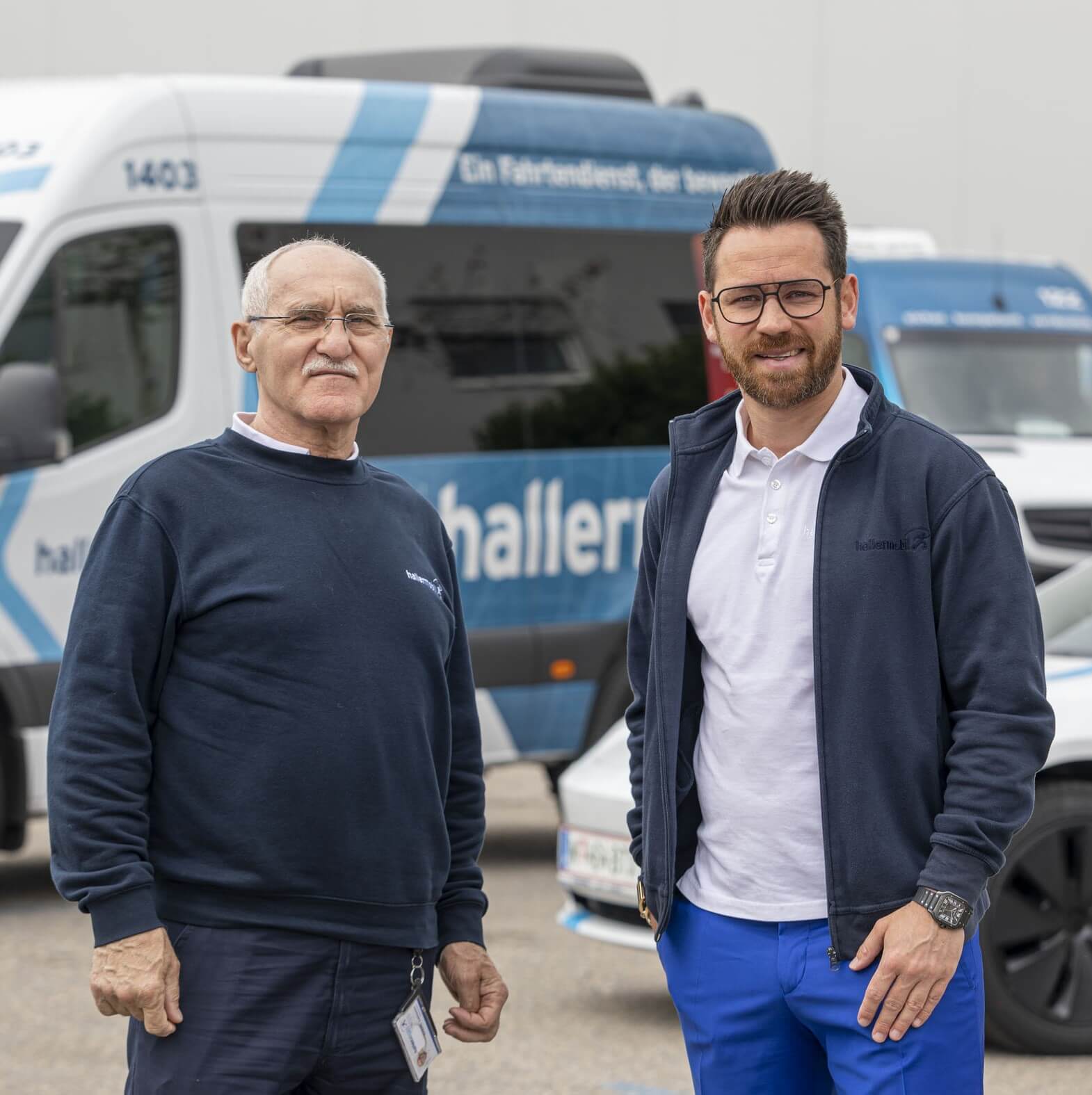 Khuseyn und Betriebsleiter Benjamin Haller stehen nebeneinander vor dem Dienstwagen und lächeln in die Kamera.