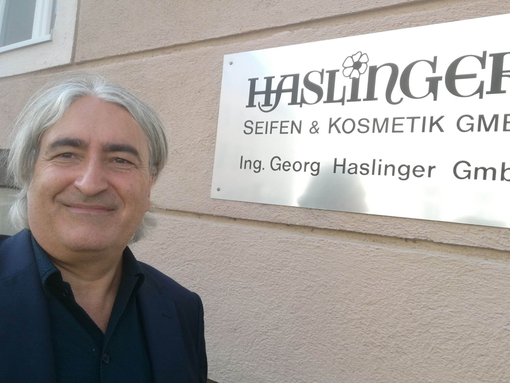 Thomas Rihl vor dem Logo der Firma Haslinger an der Fassade des Firmengebäudes.