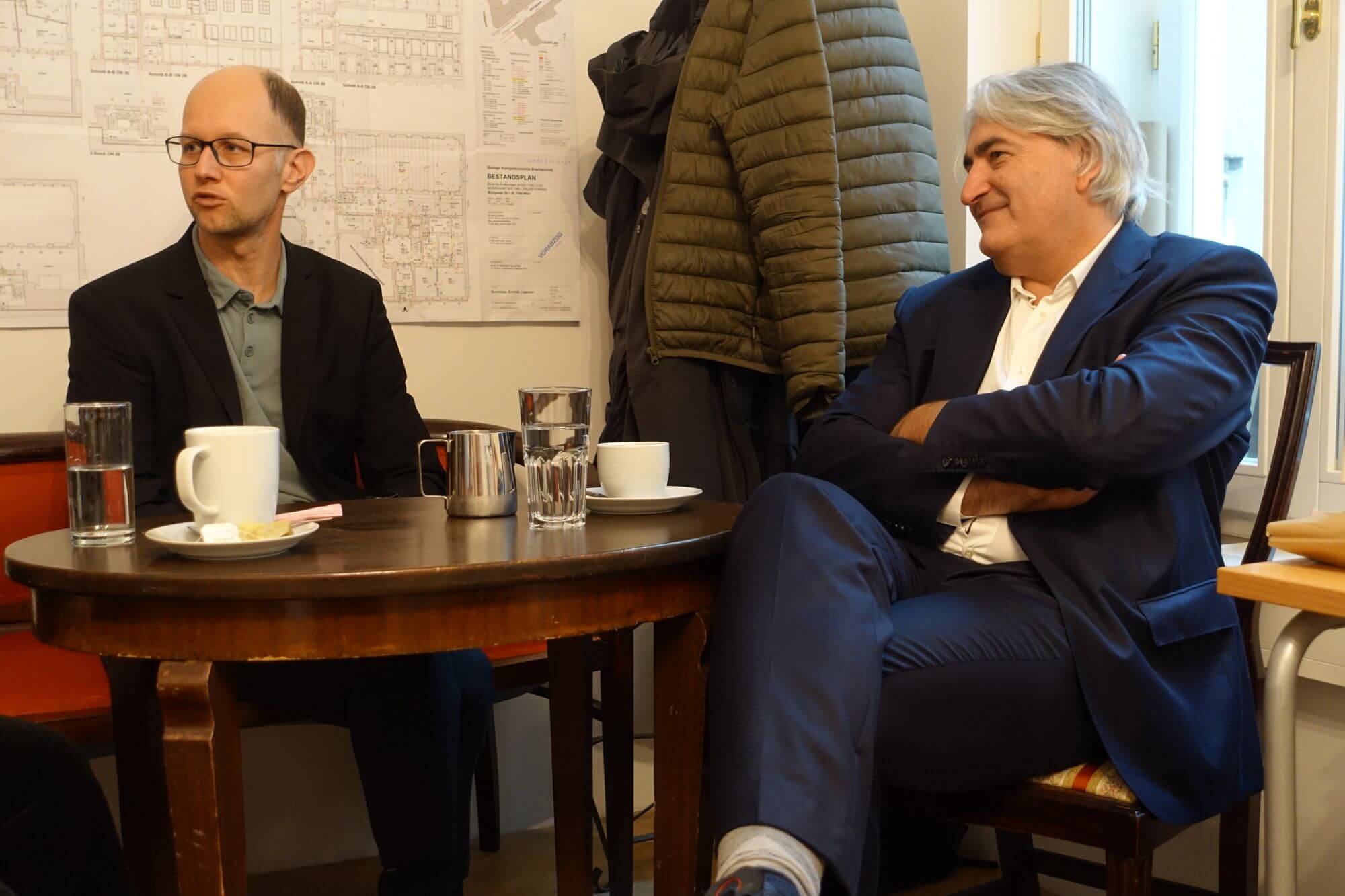 Thomas Rihl und Gerald Schmid im Gespräch an einem Tisch im Büro von Gerald Schmid.