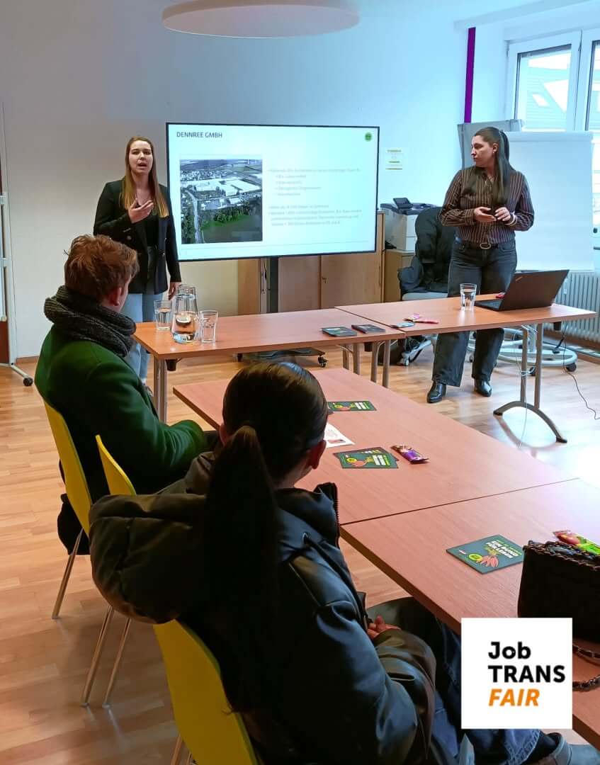 Zwei Vortragende, in der Mitte ein Smartboard mit Powerpointfolien.
