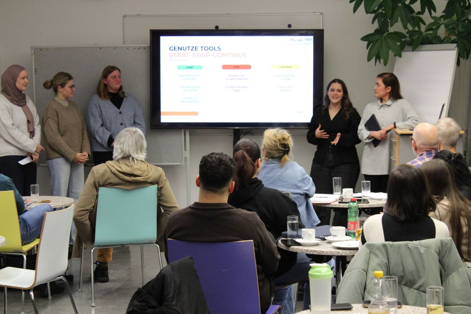 Vortragssituation mit vier Vortragenden und Publikum.